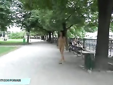 Безбашенная длинноволосая девушка гуляет по парку в голом виде